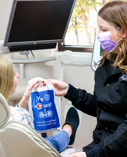 Dental Assistant wearing face mask giving bag to patient